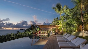 An infinity pool with lounge chairs, a wooden deck, and a view of the ocean at sunset. - Stellae (1/6 Rooms) Luxury villa (Anse de Lorient)