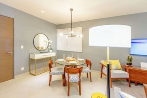 A modern dining area with a round table, chairs, and a ceiling light fixture. - Ocean-View Patio, 9 Pools & Beach Club (Akumal)
