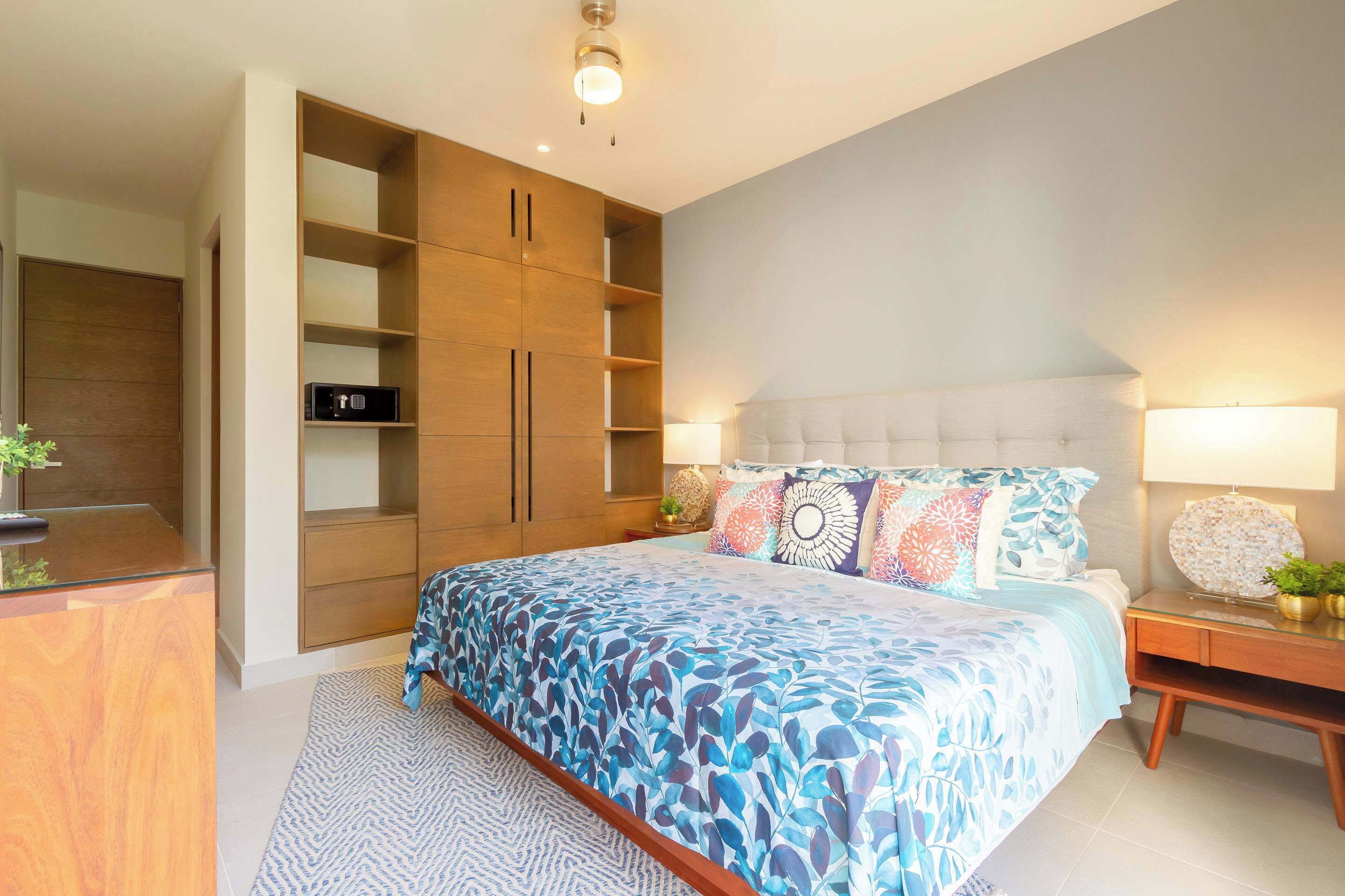 Une chambre à coucher avec un grand lit, une armoire à plusieurs compartiments, une table de chevet avec une lampe et une petite plante.