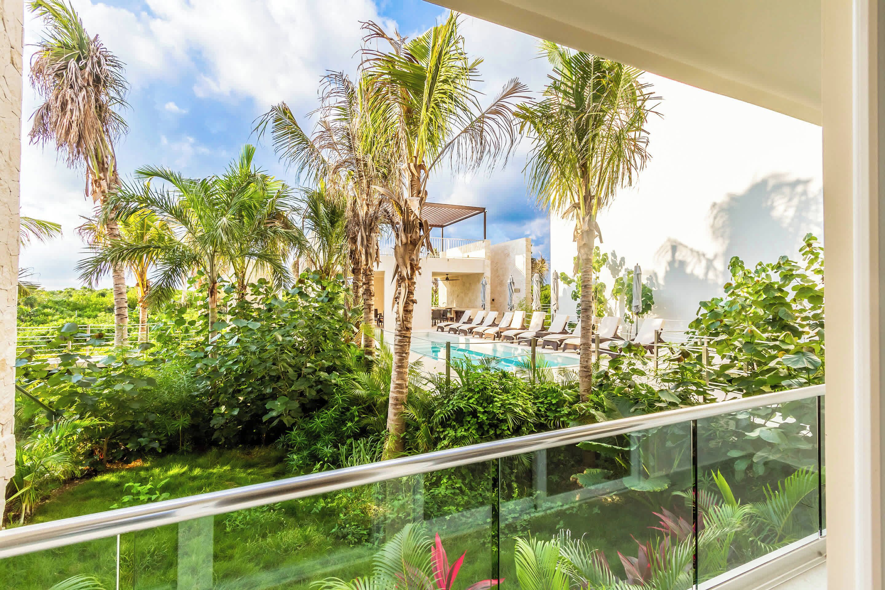 Blick auf einen Pool mit Palmen und einem Gebäude mit überdachtem Bereich.
