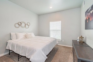 A bedroom with a bed, a window with blinds, a wall-mounted artwork, and a small table with a lantern. - Spacious Family Stay Near BYU-Idaho Campus (Rexburg)