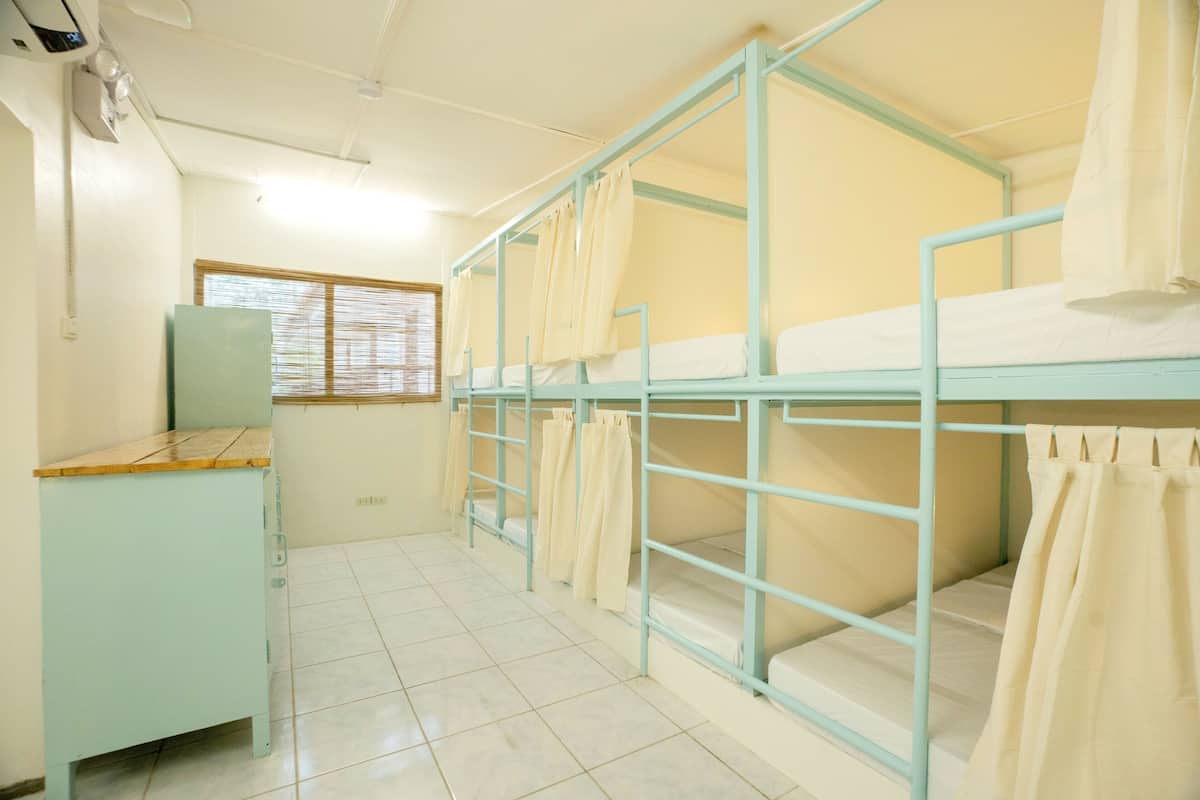 Une chambre de dortoir avec des lits superposés, un bureau et une fenêtre avec des stores.