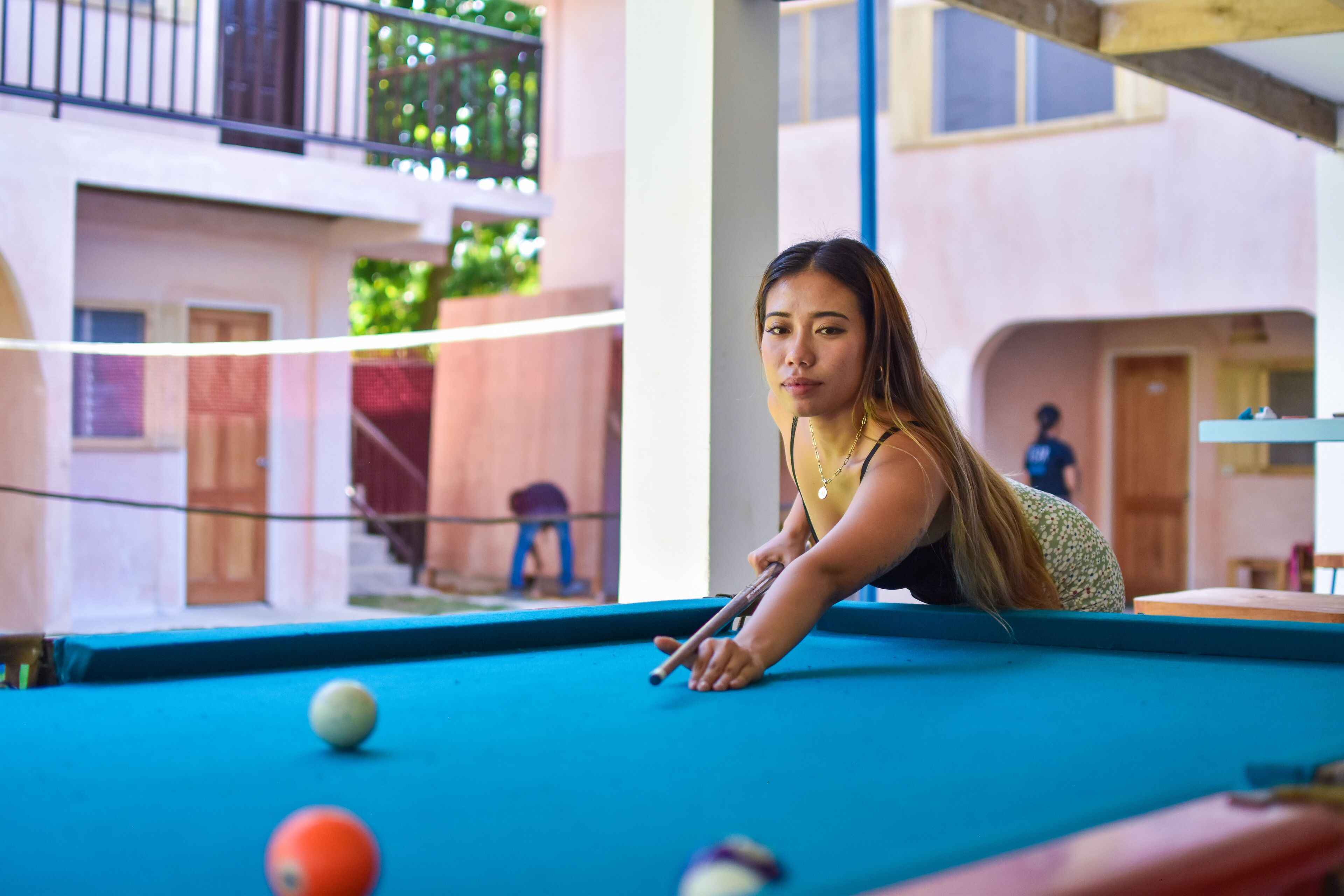 A pool table in a room with a view of a building with balconies and windows.