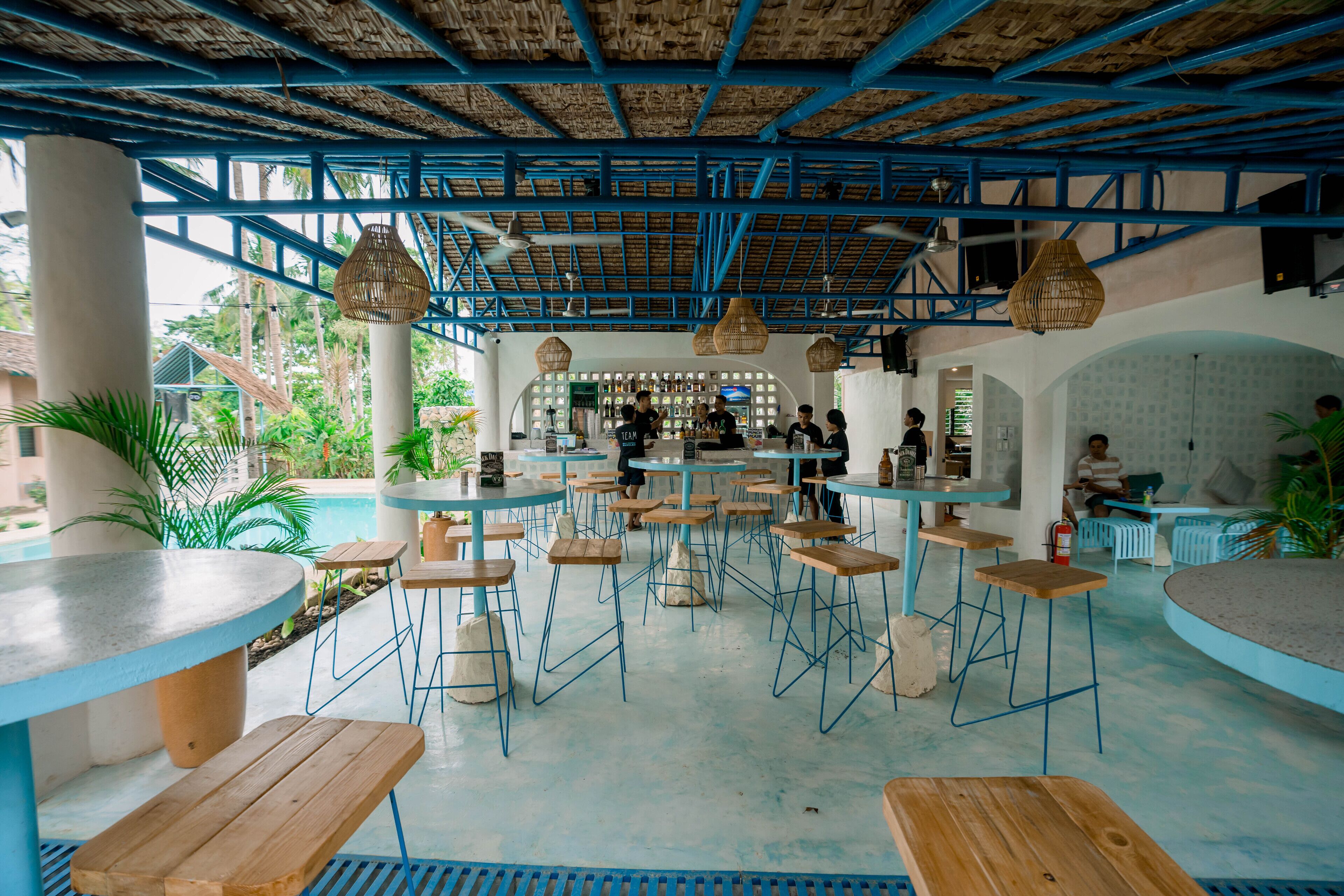 Un restaurante con decoración azul y blanca, varias mesas y sillas, y una zona de bar.