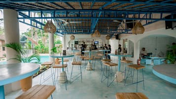 Un restaurante con decoración azul y blanca, varias mesas y sillas, y una zona de bar.