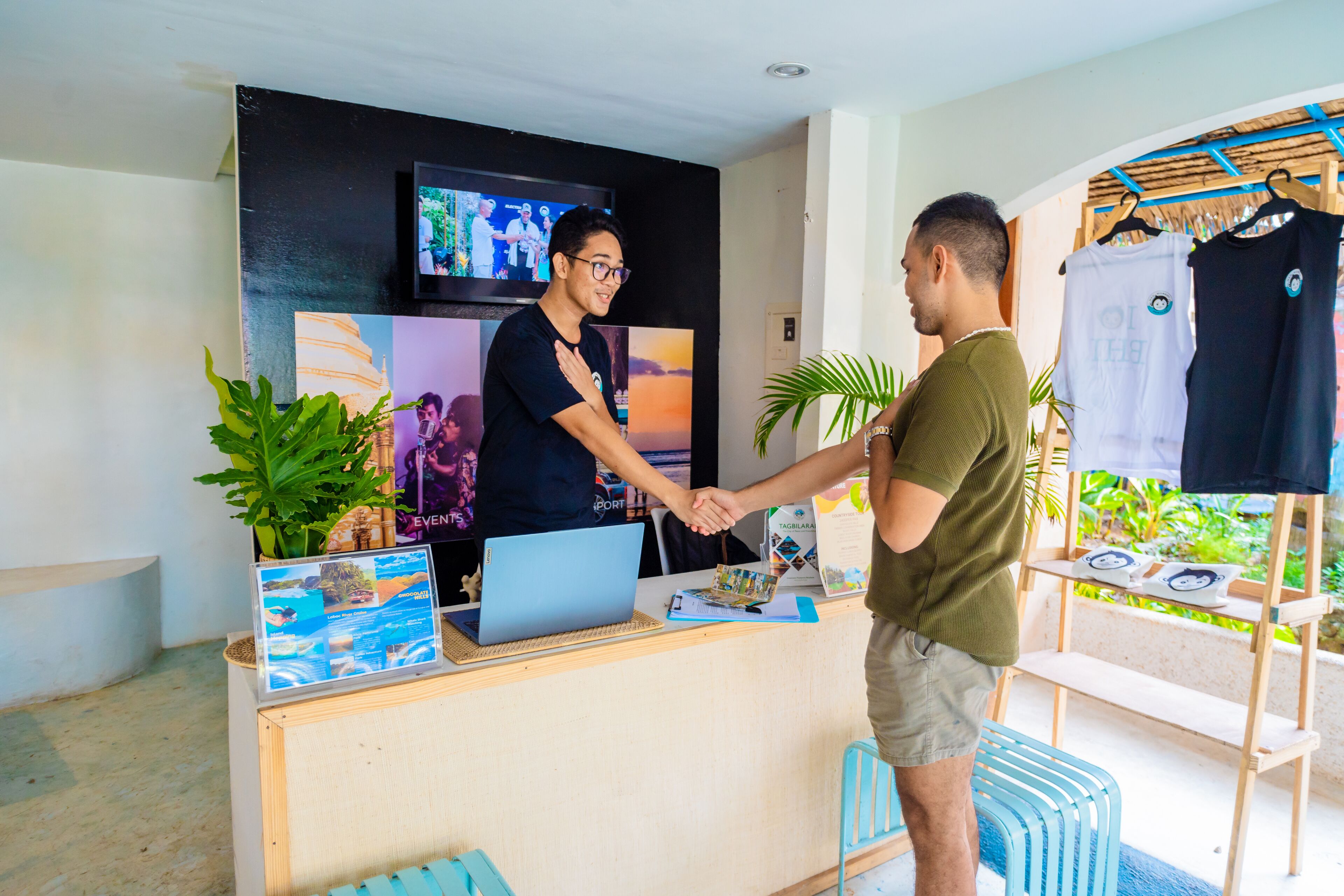 A reception desk with a laptop, a plant, and a display of brochures.