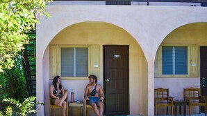 A building with two arched doorways, a small outdoor seating area with two wooden chairs and a table, and a door marked with the number 108. - Mad Monkey Panglao (Dauis)