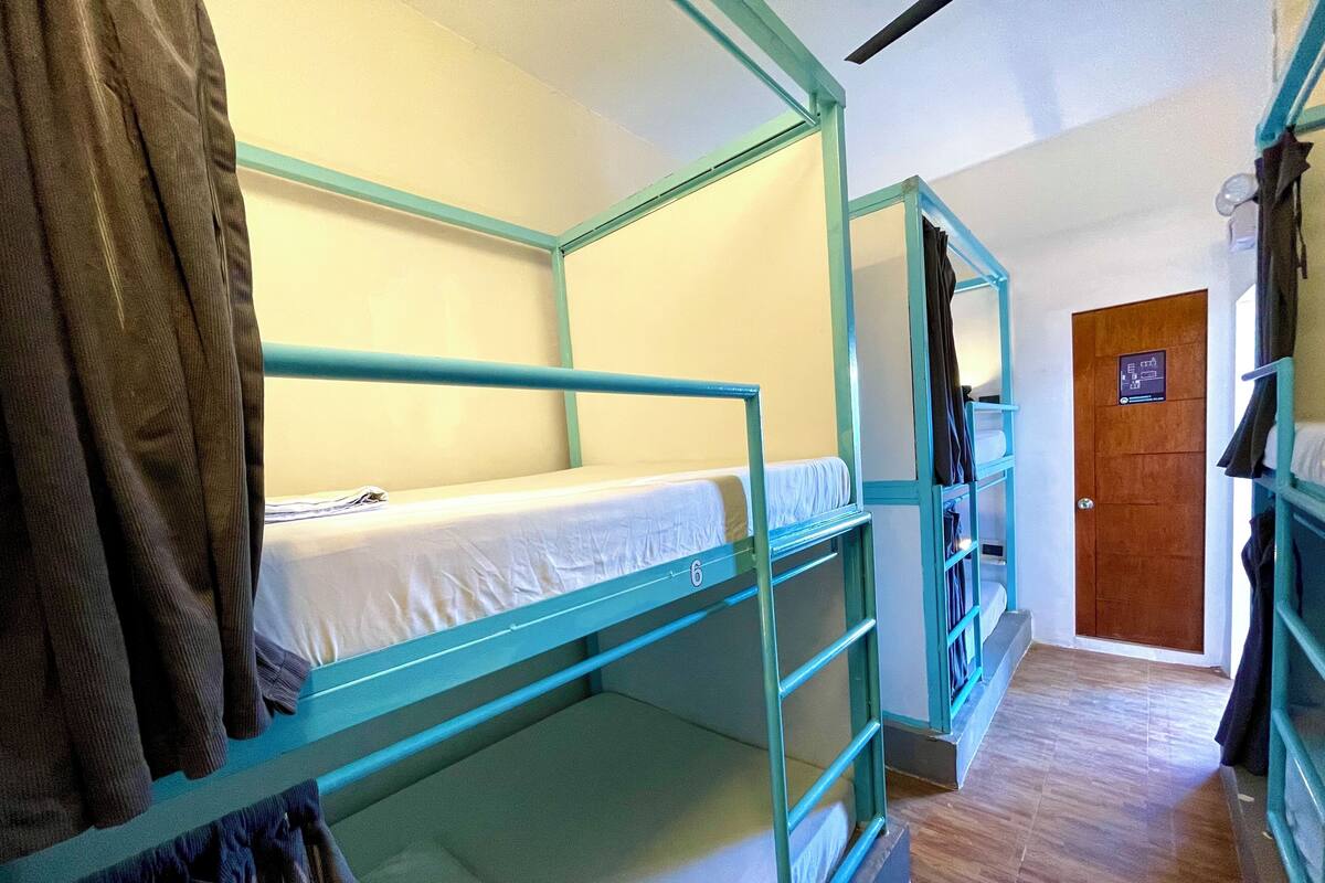 Une chambre avec un lit superposé, une porte en bois et un porte-manteau.