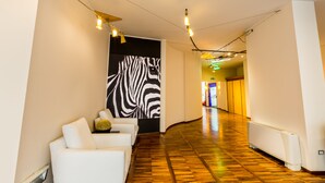 A hallway with a zebra mural, white sofas, and a wooden floor.