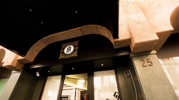 The entrance of a hotel with a prominent archway and a sign indicating it is a luxury apartment building.