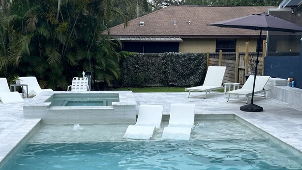 A swimming pool with white lounge chairs and a hot tub area. - Il Santuario 17 Heated Pool and Spa Close to Beach and Fifth Avenue (Naples)