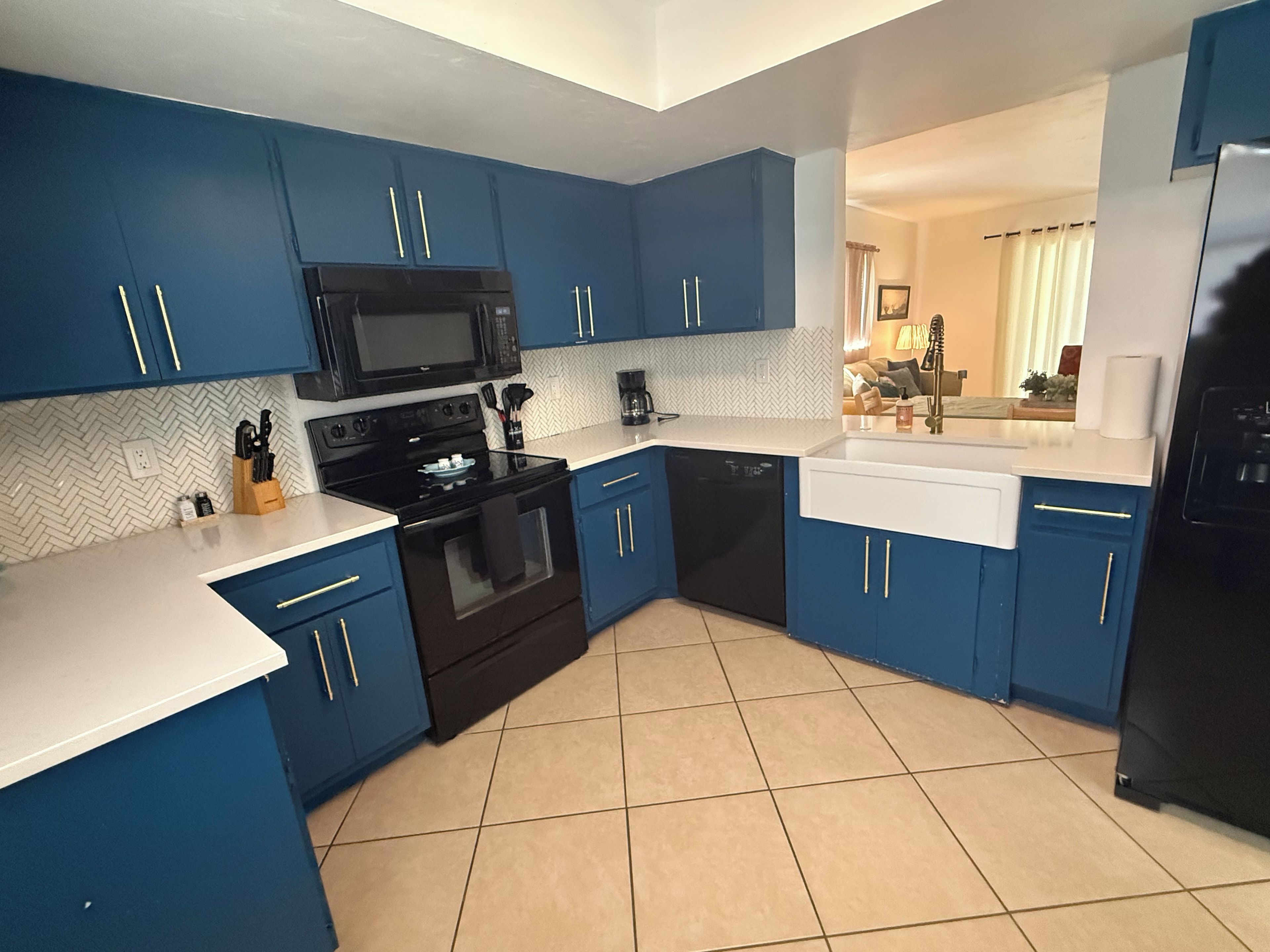 A modern kitchen with blue cabinets, a black stove, a microwave, and a dishwasher.