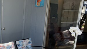 An outdoor patio area with a metal table and chairs, a potted orchid, and a painting of a seahorse on the wall. - Il Santuario 17 Heated Pool and Spa Close to Beach and Fifth Avenue (Naples)