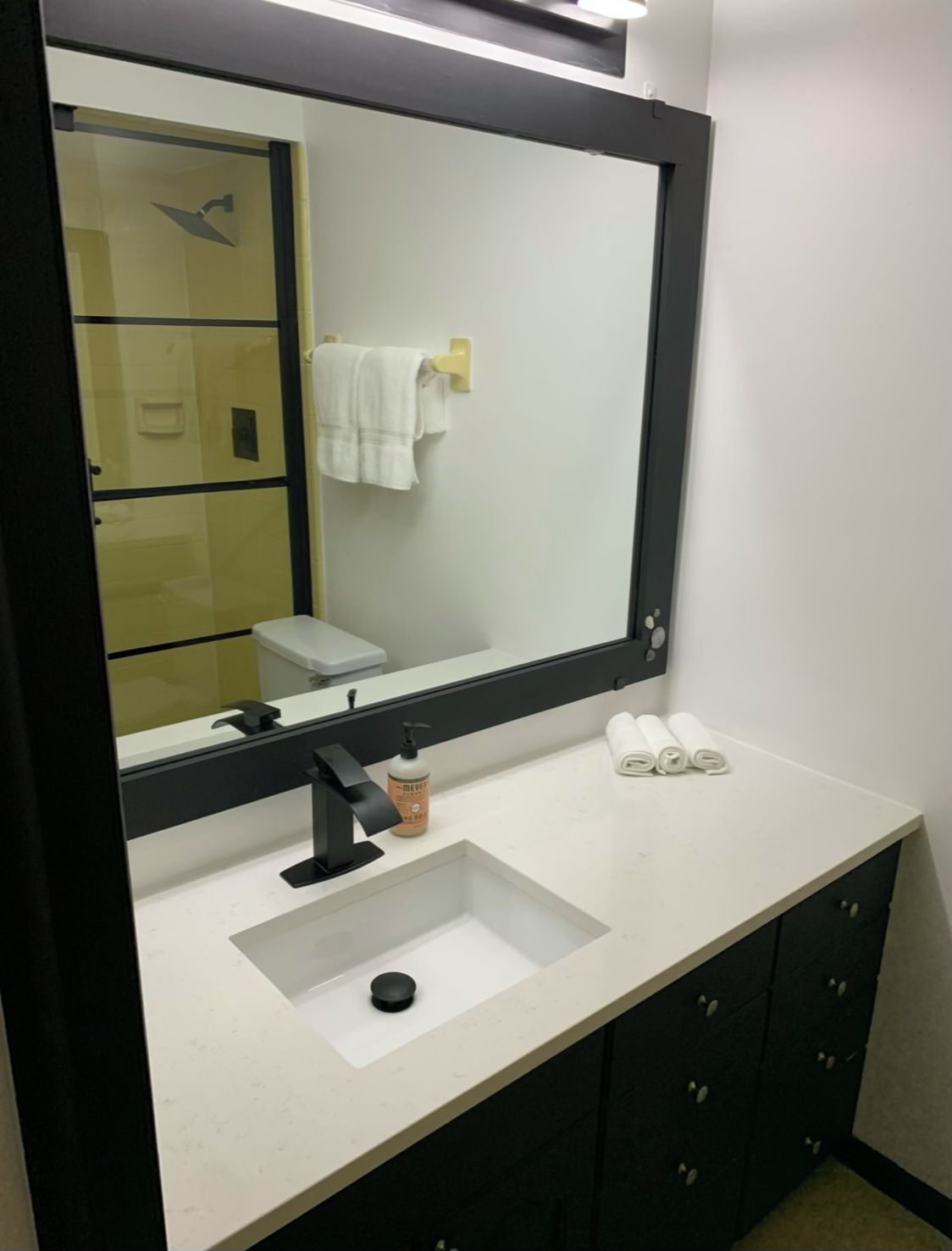 Un baño con un espejo grande, un lavabo y un inodoro.
