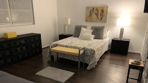 A bedroom with a bed, bedside tables, a bench, a dresser, and a painting on the wall. - Il Santuario 17 Heated Pool and Spa Close to Beach and Fifth Avenue (Naples)