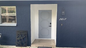 A dark blue house with a white door, a number '2617' on the wall, and a metal sign with floral designs. - Il Santuario 17 Heated Pool and Spa Close to Beach and Fifth Avenue (Naples)