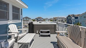 Een terras met Adirondack-stoelen, een jacuzzi en uitzicht op omliggende huizen.