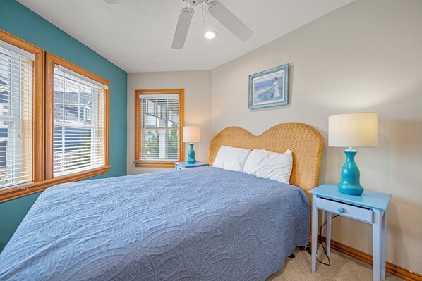 A bedroom with a bed, two bedside tables, a ceiling fan, and two windows with blinds. - White Dolphin: Hot Tub | Pool Access | Dogs OK (Corolla)