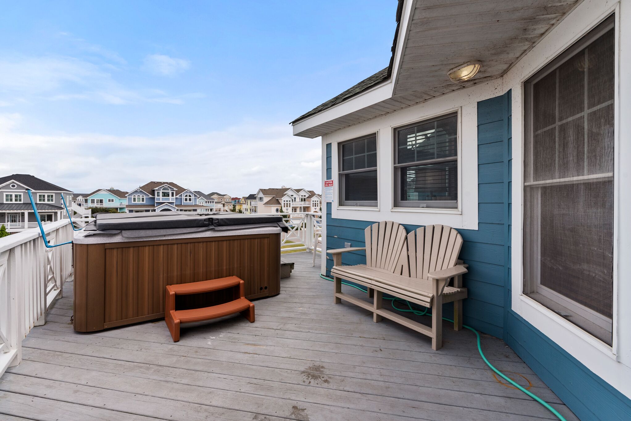 A wooden deck with a hot tub, a wooden chair, and a bench.