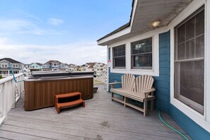 A wooden deck with a hot tub, a wooden chair, and a bench.