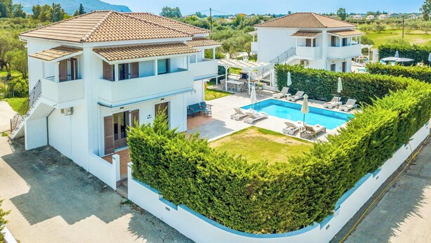 Een villa met twee verdiepingen, een zwembad, terras en een verzorgde tuin.