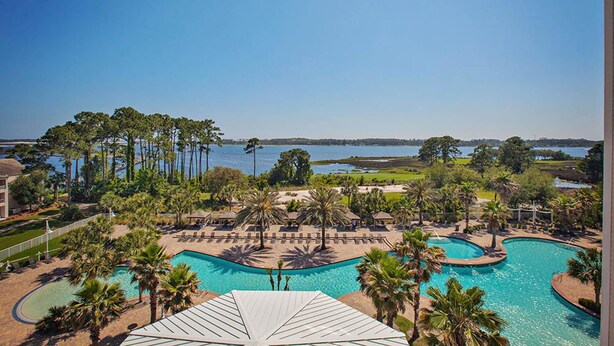 Ein Pool in einem Resort mit Blick auf einen See und Palmen.