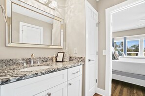 A bathroom with a marble sink, a large mirror, and a window seat with a view.
