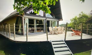 Ein modernes Hausboot mit Deck, Sitzgelegenheit im Freien und einer Treppe zum Eingang.