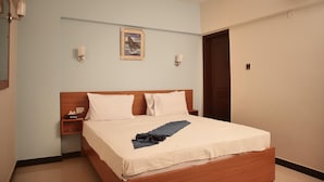A neatly arranged hotel room with a bed, bedside tables, a framed picture on the wall, and an air conditioning unit. - Remarkable Diamond Apartment Dha Defense Karachi (Karachi)
