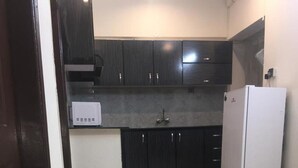 A kitchen with dark cabinets, a white refrigerator, and a microwave. - Remarkable Diamond Apartment Dha Defense Karachi (Karachi)
