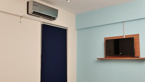 A room with a closed window, an air conditioning unit, and a mounted television on the wall. - Remarkable Diamond Apartment Dha Defense Karachi (Karachi)