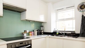 Una cocina moderna con armarios blancos, una estufa negra y una ventana con persianas.