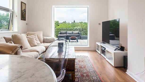 Una sala de estar moderna con un ventanal grande, un sofá, una mesita de centro y un televisor.