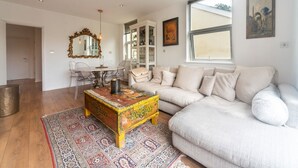 Amplia sala de estar con un sofá grande, una mesa de centro y un comedor con sillas y una mesa.