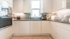 Una cocina moderna con armarios blancos, un horno Bosch, una cafetera y un tostador.