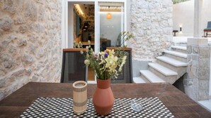 A stone-walled room with a checkered table, a vase with flowers, and a staircase leading to an upper level. - House of Nice Memories (Orebic)