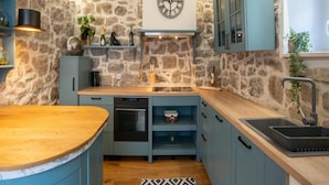 A kitchen with a stone wall, a wooden countertop, a built-in oven, and a sink. - House of Nice Memories (Orebic)