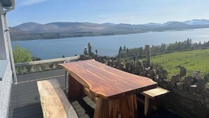 A wooden deck with a bench and a table overlooking a lake with mountains in the distance. - 6 Ensuite Bedrooms-sleeps 12-garden-sea & Mtn View (Blackwater Bridge)
