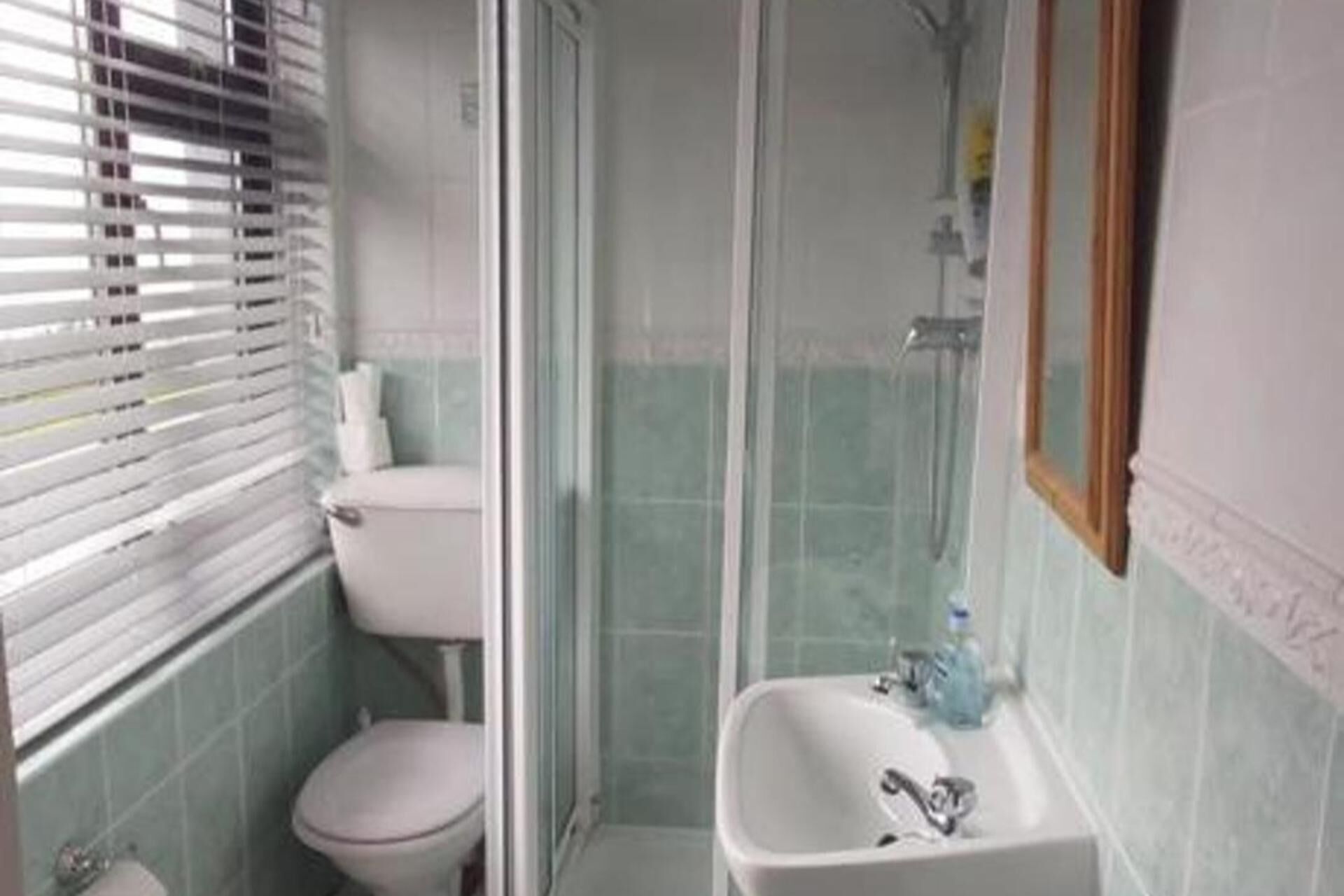 Un baño con inodoro, cabina de ducha y lavamanos.