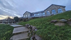 A stone building with a balcony and large arched windows, situated on a grassy hill. - 6 Ensuite Bedrooms-sleeps 12-garden-sea & Mtn View (Blackwater Bridge)