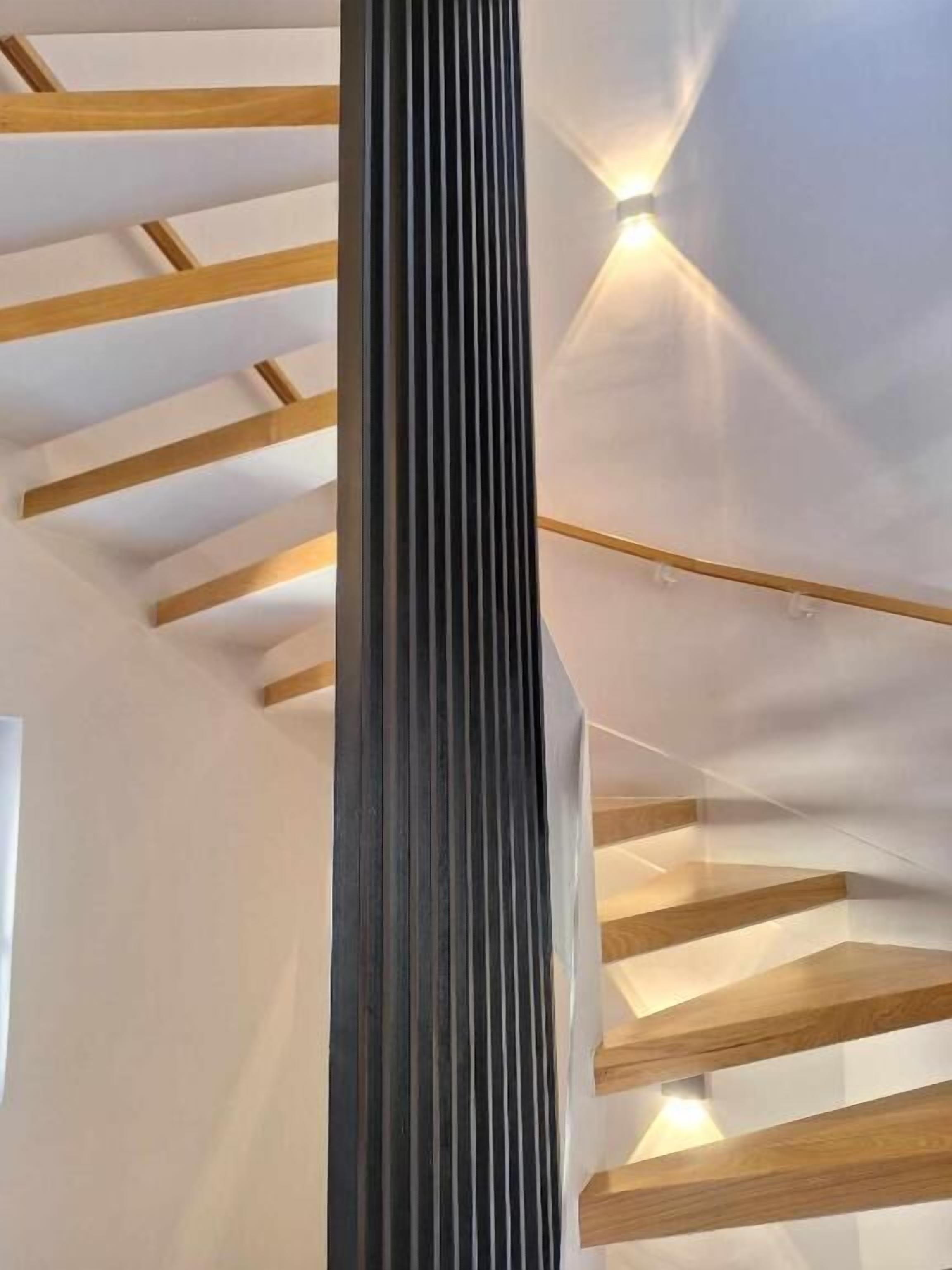 Een moderne trap met houten balken en een centrale kolom.