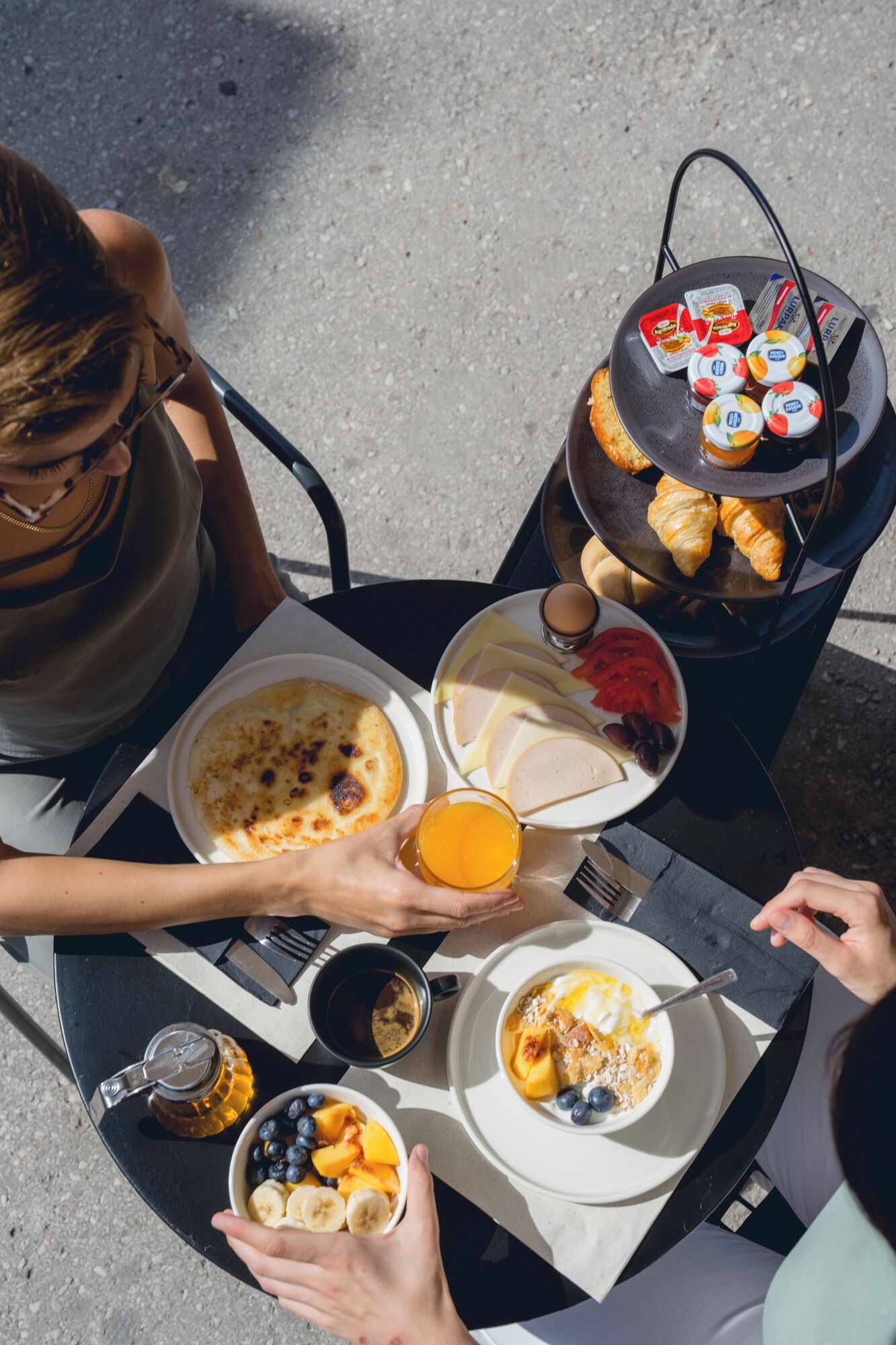 Une table dressée pour le petit-déjeuner, avec divers aliments, notamment une assiette contenant des œufs, des toasts et un verre de jus d’orange.