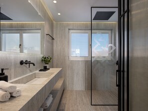 Un baño moderno con un espejo grande, un lavamanos con grifo y un box de ducha de vidrio.