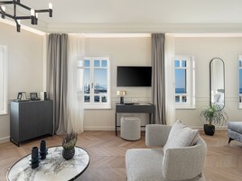 Una sala de estar moderna con televisor de pantalla plana, una mesa redonda con jarrones, un sofá y una planta en maceta.