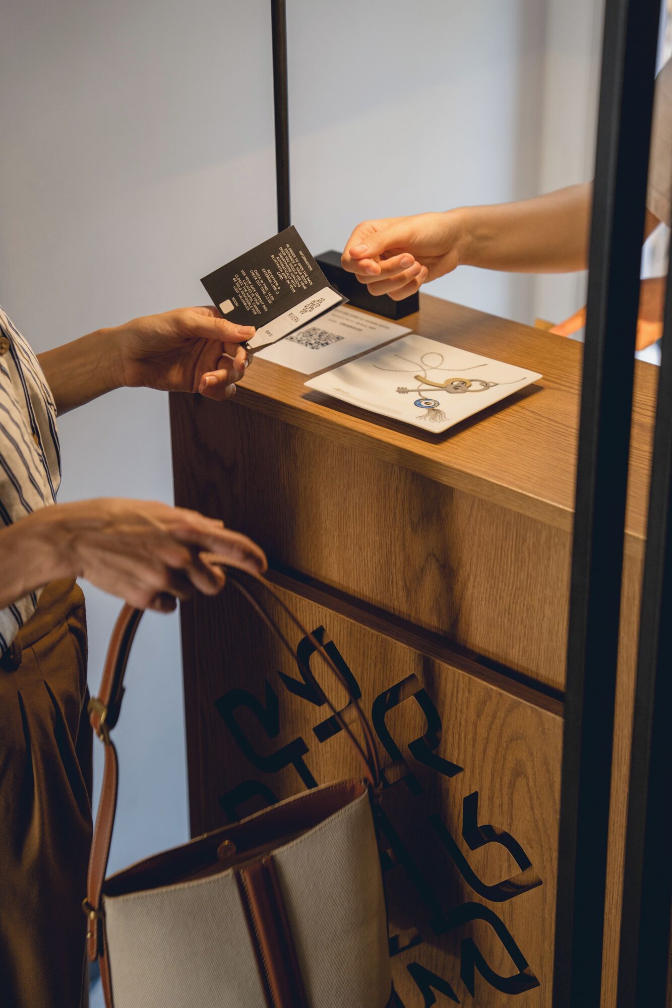 A person handing over a card to another person at a wooden counter with a QR code and a card with a drawing on it.