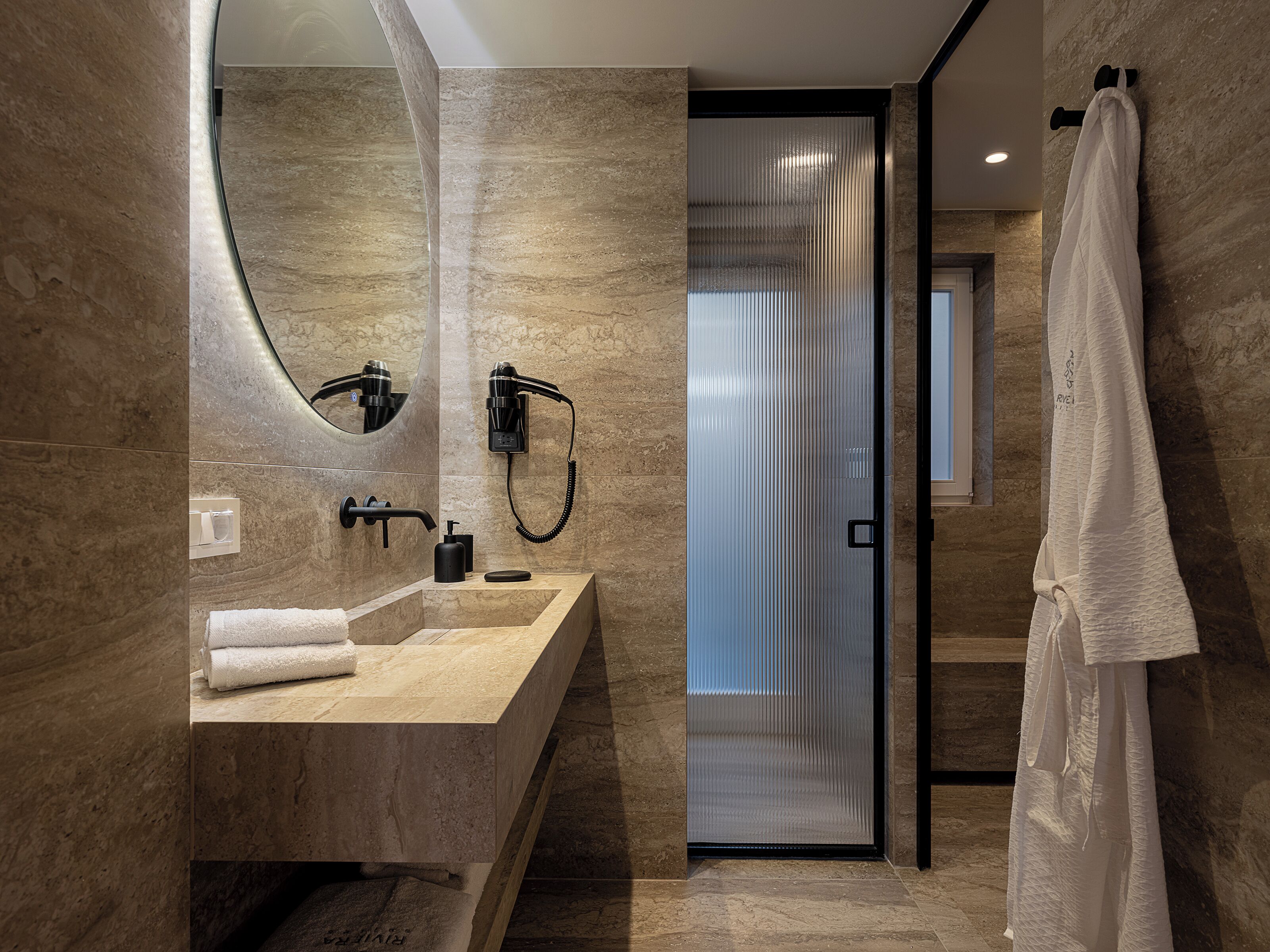 Une salle de bain moderne avec un comptoir en marbre, un grand miroir, un porte-serviettes et un rideau de douche.