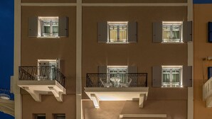 A multi-story hotel with balconies, a stop sign, and illuminated signage. - Riviera Suites (Chania)