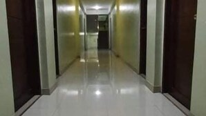 Un pasillo largo y estrecho con un suelo de baldosas brillantes y puertas de madera a ambos lados.