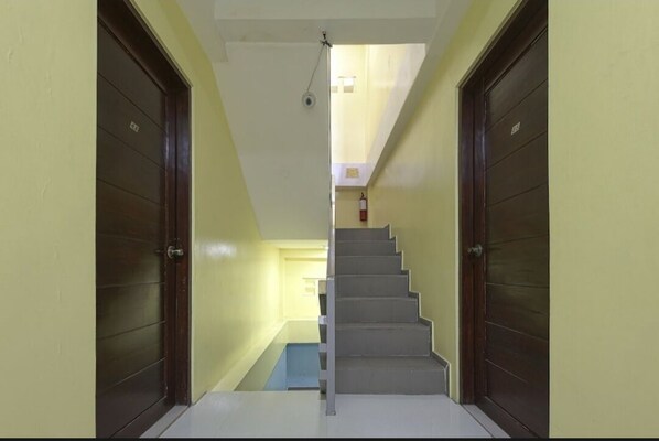 A staircase leading to an upper floor with a fire extinguisher on the wall. - Alicia Apartment (Parañaque)