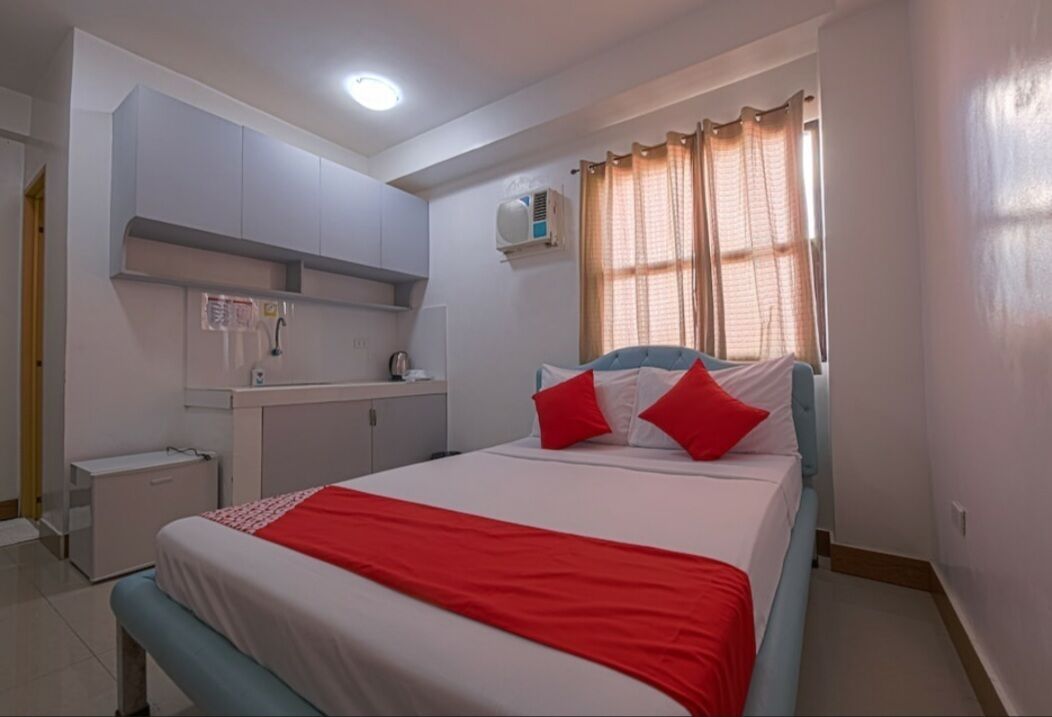 A bedroom with a bed, a nightstand, a wardrobe, and a window with curtains.
